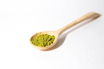 Green powder of Japanese matcha tea in a teaspoon. Matcha on a white background, isolated