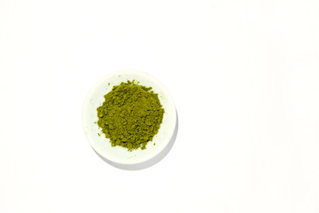 Green powder of Japanese matcha tea on a platter, isolated on a white background. Loose powder