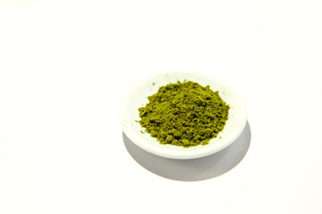Green powder of Japanese matcha tea on a platter, isolated on a white background. Loose powder