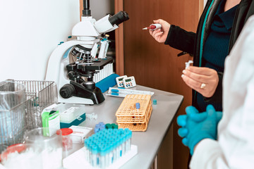 Working in the lab, professor teaching student about using micropipette