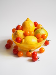 still lifes of bright yellow lemons and with yellow and orange cherry tomatoes in a yellow transparent bowl