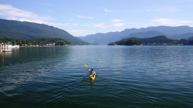 Aerial view over Kayaker paddling towards Mountains on sunny Day