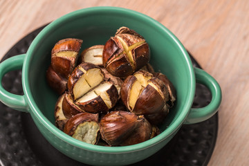 Edible roasted chestnuts in a green bowl, European seasonal treat