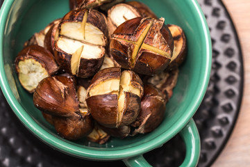 Edible roasted chestnuts in a green bowl