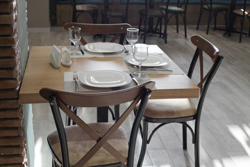 Dining table served with plates, glasses, forks and knives.
