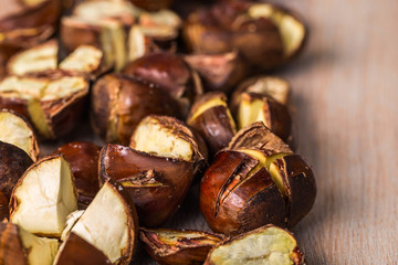 Lightly roasted edible chestnuts scattered on a wooden surface