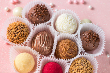 Cute chocolate candies with sugar decorations on a pink shiny background