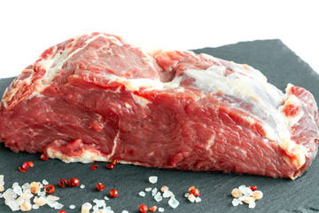 Fresh raw beef steak on a black  slate plate isolated white background. Raw rib eye steak on a slate plate with salt and pepper.