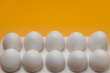 Fresh eggs. White farm eggs in a tray on an orange background close-up. Copy space.