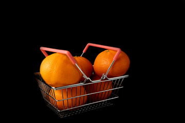 Fresh juicy tangerines in a shopping basket on a black background close-up. Juicy sweet fruits in the supermarket mini-basket. Copy space.