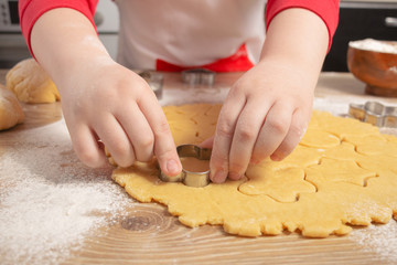 Child's hands make traditional Christmas cookies at home. Raw dough and cutters for holiday cookies. Cooking and home concept. Сlose up