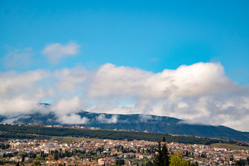 Low floating clouds over a village in the mountains. Panoramic view of low hanging white clouds in the mountains.