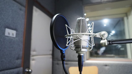 Sound production recording studio with microphone and shock mount and pop filter on tripod which...
