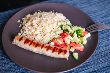 with pork sausage bulgur and tomato and cucumber salad. Close-up