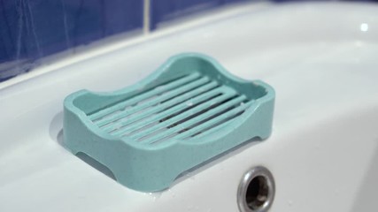 Girl hand with a beautiful manicure takes a piece of soap with soap dishes on a white sink. Woman Washing Her Hands With Water, Soap and Foam. Cleaning the skin. Avoid virus corona COVID. Close Up 4k