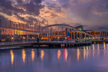 Rambla de Mar in Port Vell in Barcelona, Catalonia, Spain. Architecture and landmark of Barcelona. Sunset cityscape of Barcelona.