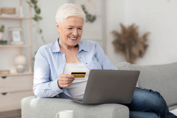 Fototapeta na wymiar Smiling Aged Woman Making Online Shopping With Laptop And Credit Card