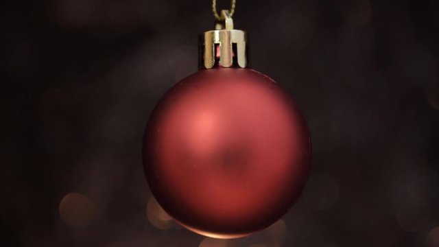 Red Christmas bauble hanging on warm dark background macro shot