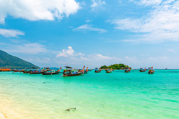 Obraz premium Long tail boats in small harbor at Ko Lipe island, south Thailand. Tropic and exotic island is symbol of tropical paradise, part of Tarutao national nature park. Vibrant colors, turquoise water.