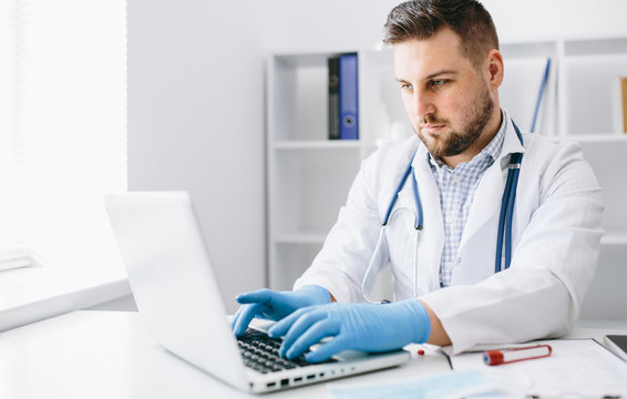 Young handsome doctor in gloves with patient online consultate
