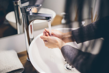 Young woman wash hands with soap in bathroom. Trendy coronavirus covid-19 concept