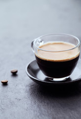 Coffee in glass cup on dark stone background. Close up.	