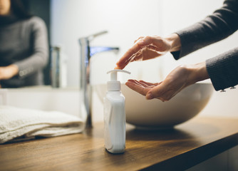 Young woman wash hands with soap in bathroom. Trendy coronavirus covid-19 concept