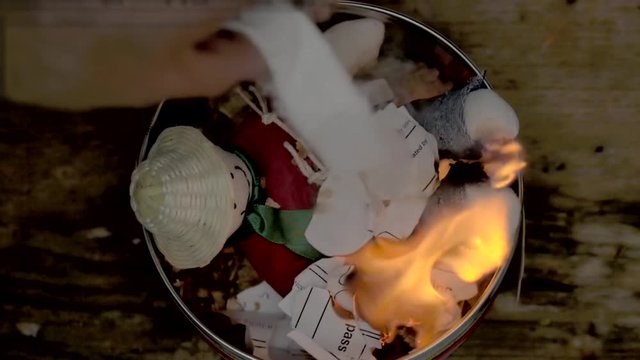 Sorcery witchcraft voodoo ritual with a doll being thrown out inside a bowl with fire to make a curse spell with him.  Muñeco de año viejo.