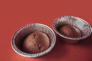 chocolate cupcakes in foil baking dish on Marsala background. Brown muffins in foiled baking forms