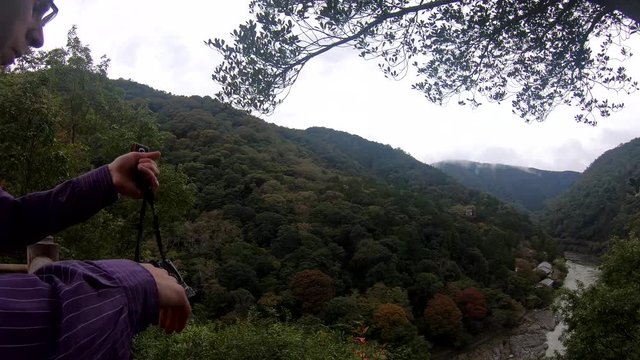 Man is enjoying nature view in Kyoto. Than takes his camera to take some photos.