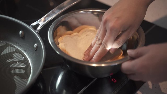 White bread is placed into a bowl of whisked egg in preparation to make french toast camera pans accross to follow bread slice being placed into a pan.