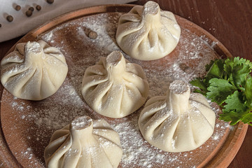 cooked raw khinkali on  kitchen board with herbs and pepper. Top view of a traditional Georgian dish
