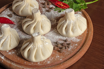 cooked raw khinkali on  kitchen board with herbs and pepper. Top view of a traditional Georgian dish