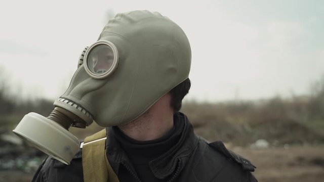 The guy in the gas mask looks around. average plan. on the background dump