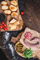 Bruschettes, vegetables, arugula, pieces of smoked dried sausage on an old wooden table. Ingredients of the Italian snack.