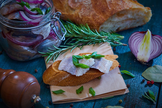 Herring, red onion and slice of rye bread on an old wooden table