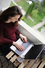 Woman working on a laptop on balcony during corona virus quarantine. Home office