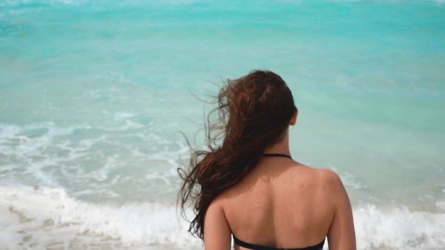 brunette girl goes to the ocean and the wind develops her hair