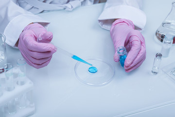Biochemist`s hands in gloves are conducting chemical experiments in lab. chemist works with lab glassware close up