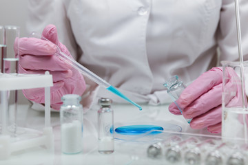 Biochemist`s hands in gloves are conducting chemical experiments in lab. chemist works with lab...