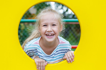 Beautiful cheerful little girl on the Playground. Long blond hair. Happy childhood. Summer holidays. Bright yellow. Round frame.