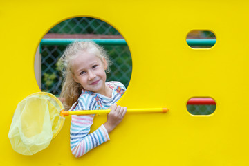 Beautiful little girl with a butterfly net on the Playground. Long blond hair. Happy childhood. Summer holidays. Bright yellow.