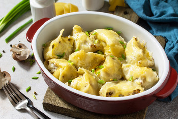 Italian pasta Conchiglioni Rigati stuffed with chicken, mushrooms, baked with cheese in bechamel sauce on a gray stone countertop.