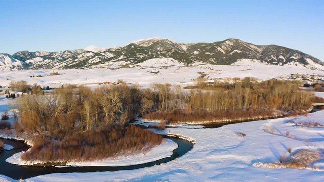 Pan across snowy river and forest