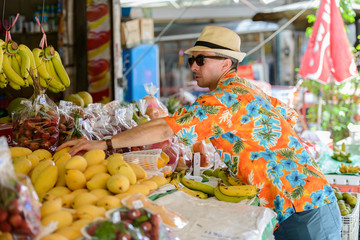 Young handsome tourist man shopping at the street market