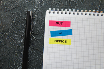 Out of office, message on colorful sticky notes. Workspace with note and pen. Work from home concept.