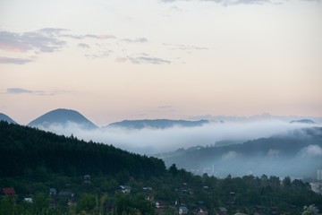 Naklejka premium Sunrise and sunset, beautiful clouds over the meadow, hills and buildings in the town. Slovakia