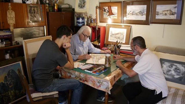 Learning to paint, an old painter shows young people how to paint watercolors, teaches them that painting technique, artistic family, father, son, grandson