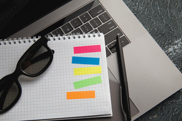 Creative workspace with laptop keaboard, glasses, pen and note for working at home. Colorful sticky notes for text.