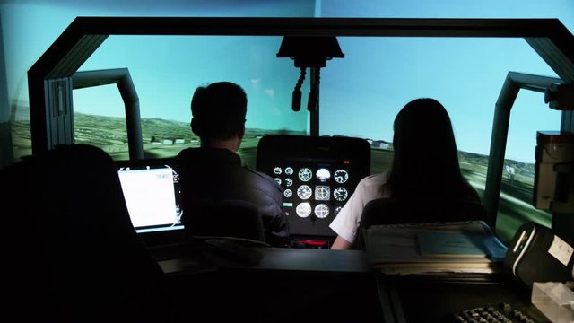 MS Rear view of student pilots in helicopter flight simulator during take off